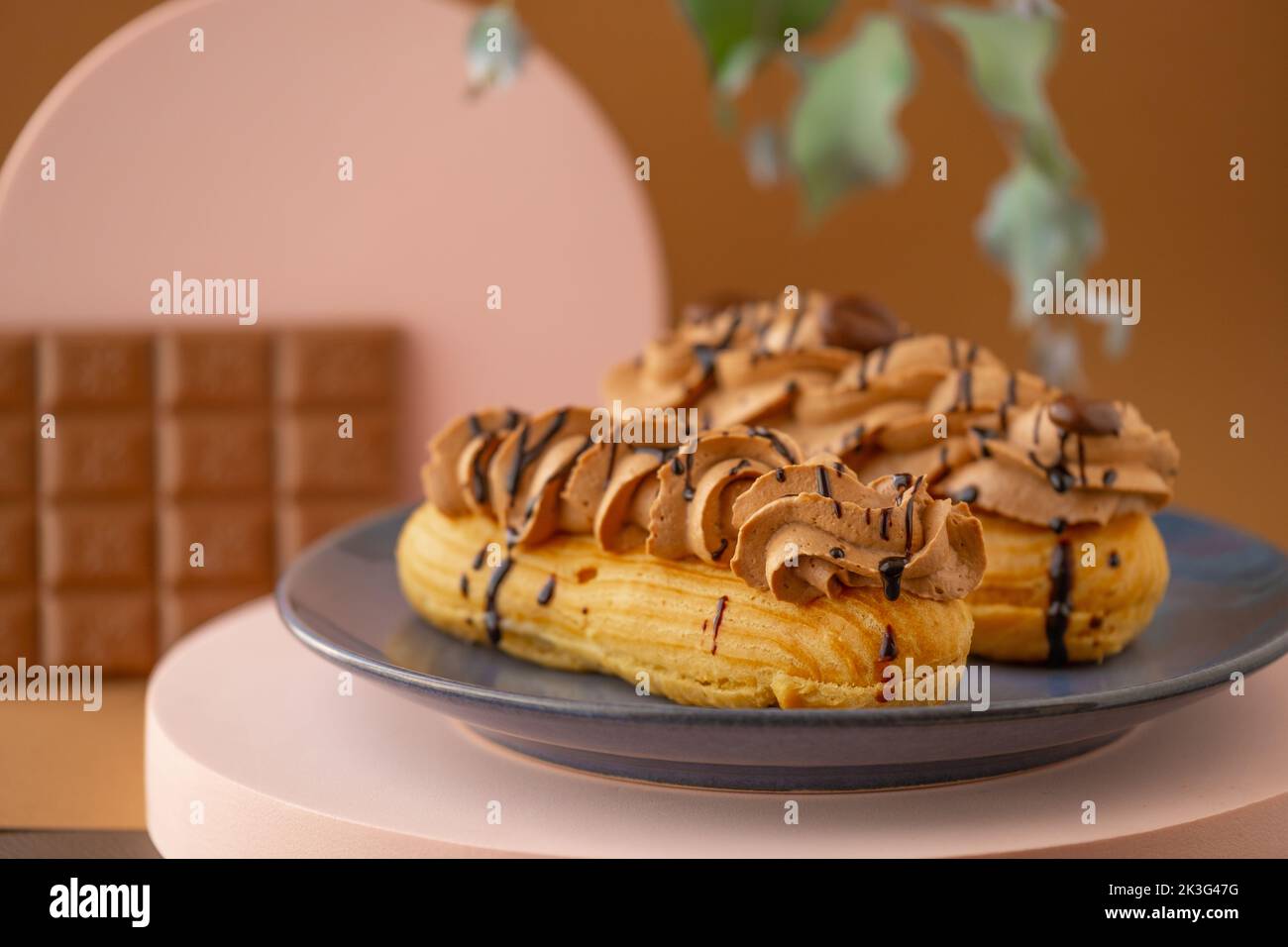 Eclairs cakes.Custard cakes with chocolate cream and chocolate bar on brown background.Sweets and desserts. Baked goods and desserts.Eclairs cakes. Stock Photo