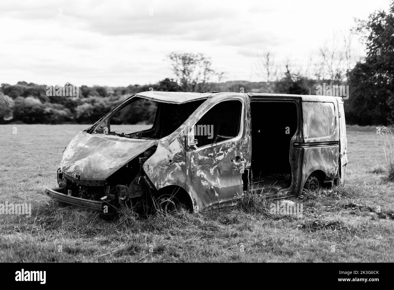 A burnt out worker's van rusty and abandoned in the middle of a field in the countryside Stock Photo