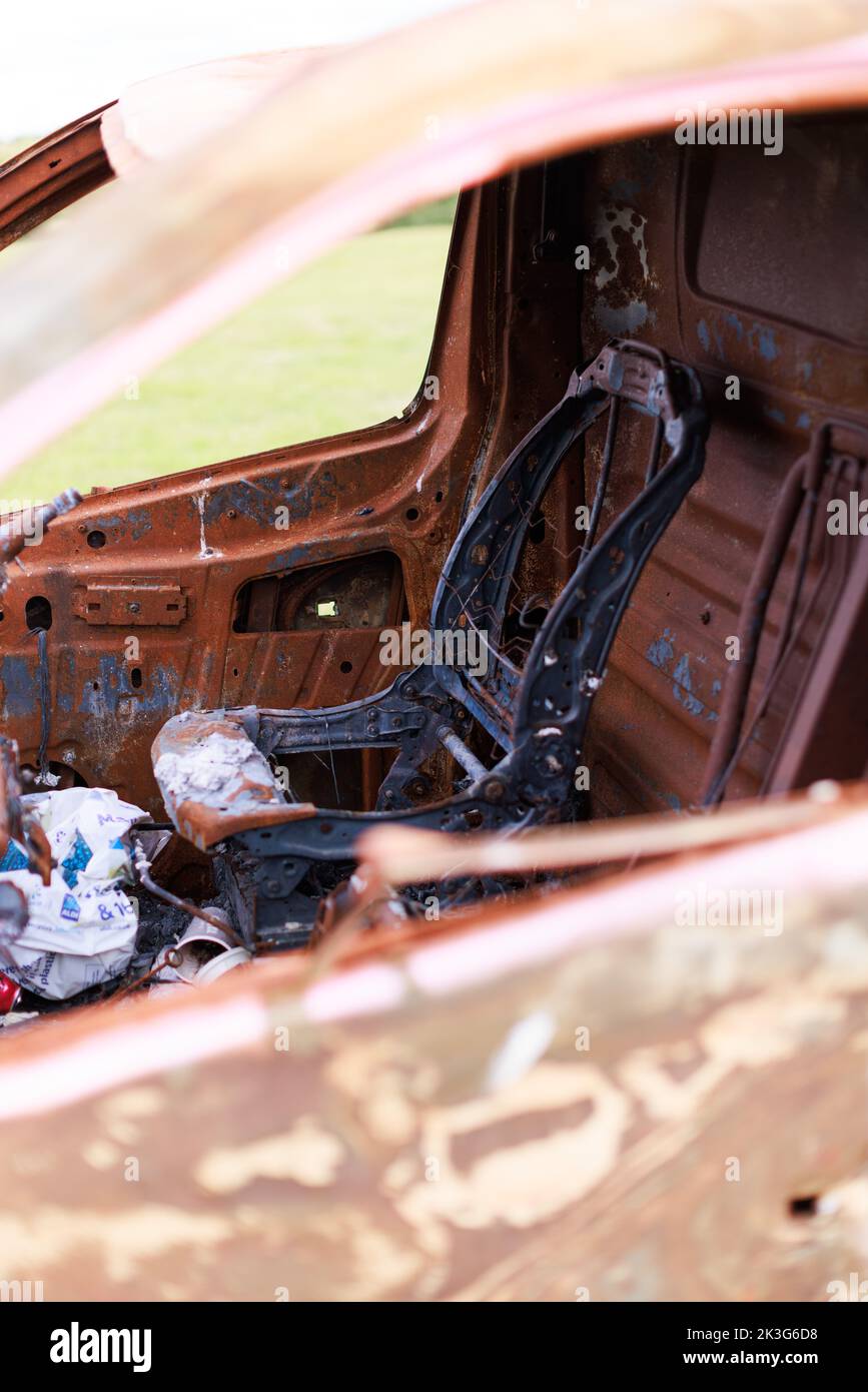 Close up of a burned/ burnt driver's seat in a burned out van in a field Stock Photo