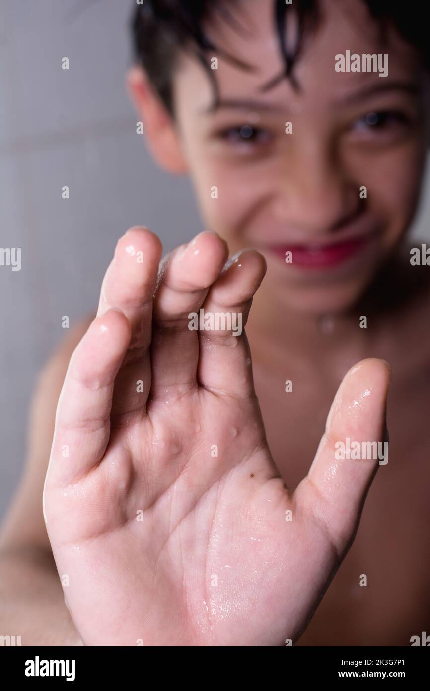 Fun and happy boy enjoying his bath while he stands under running water. Child bathes at home healthy childhood. Stock Photo