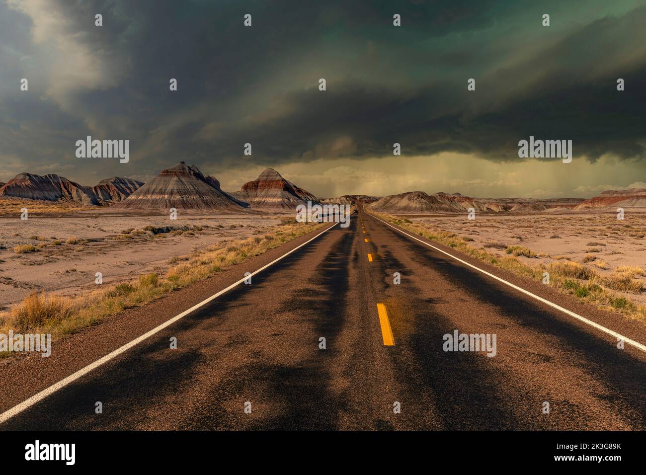 The remote roadway deep in the heart of the Petrified Forest National Park shows the beautiful mountain scenery of the painted desert during a storm. Stock Photo