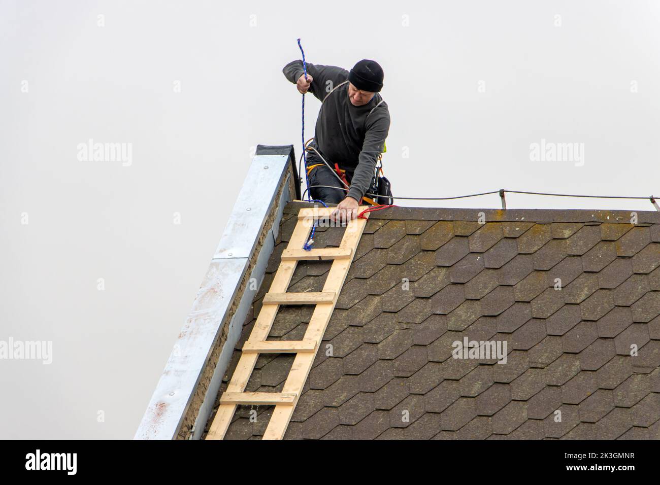A repairman with a ladder is repairing the roof Stock Photo
