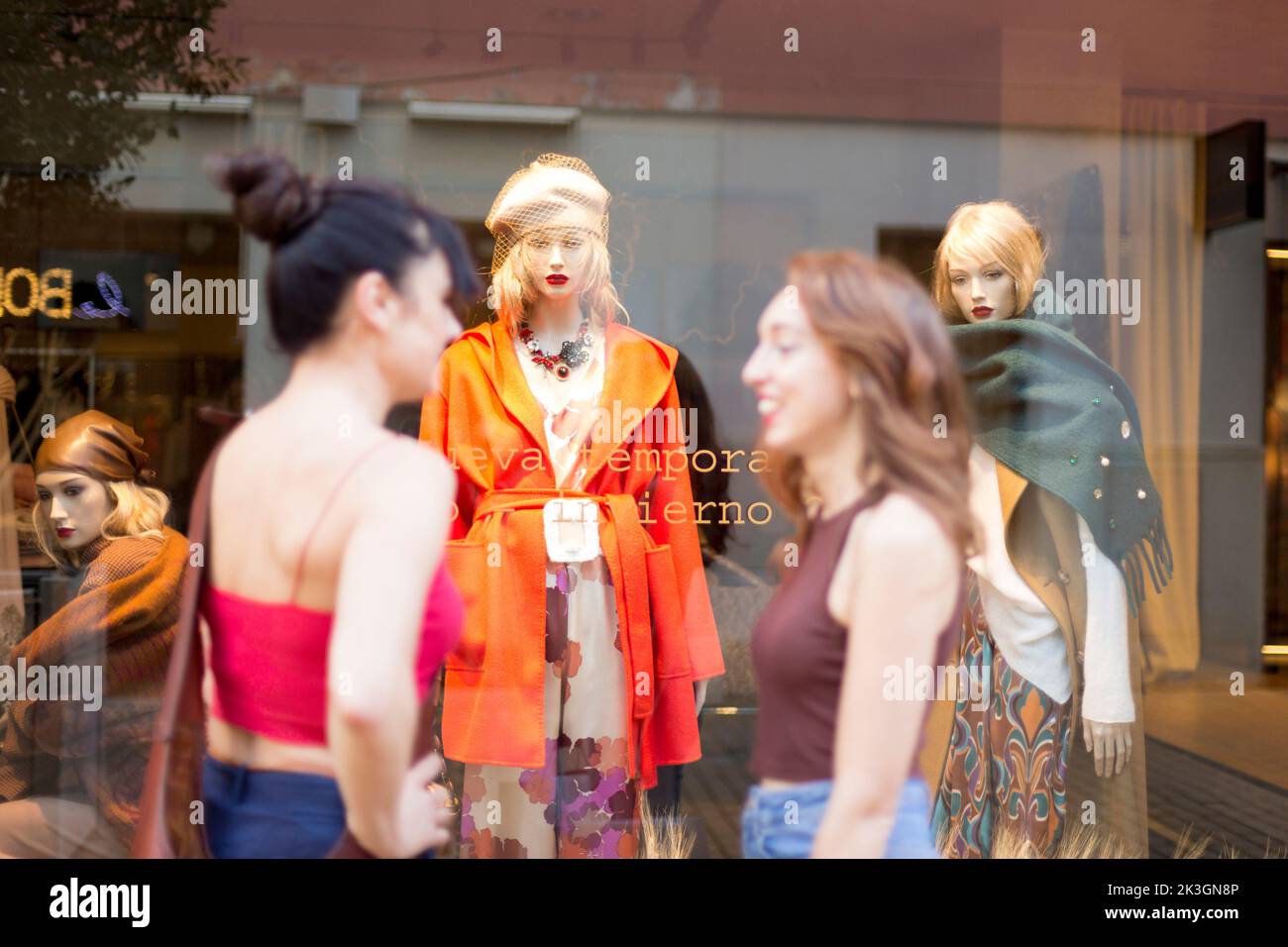 Mannequin in a clothes shop with two friends talking in front of the