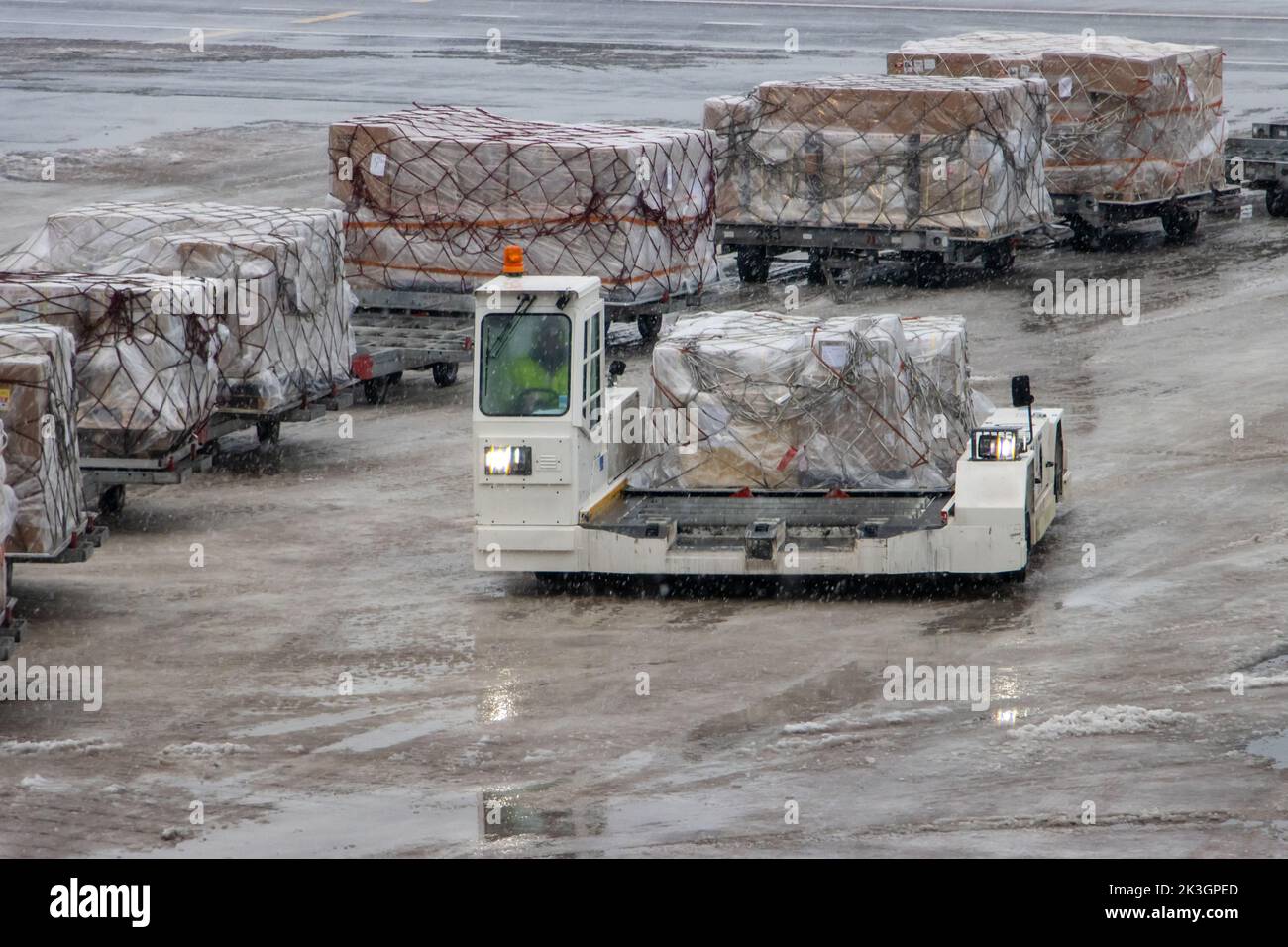 A vehicle loaded with air cargo is driving on a snowy airport Stock Photo