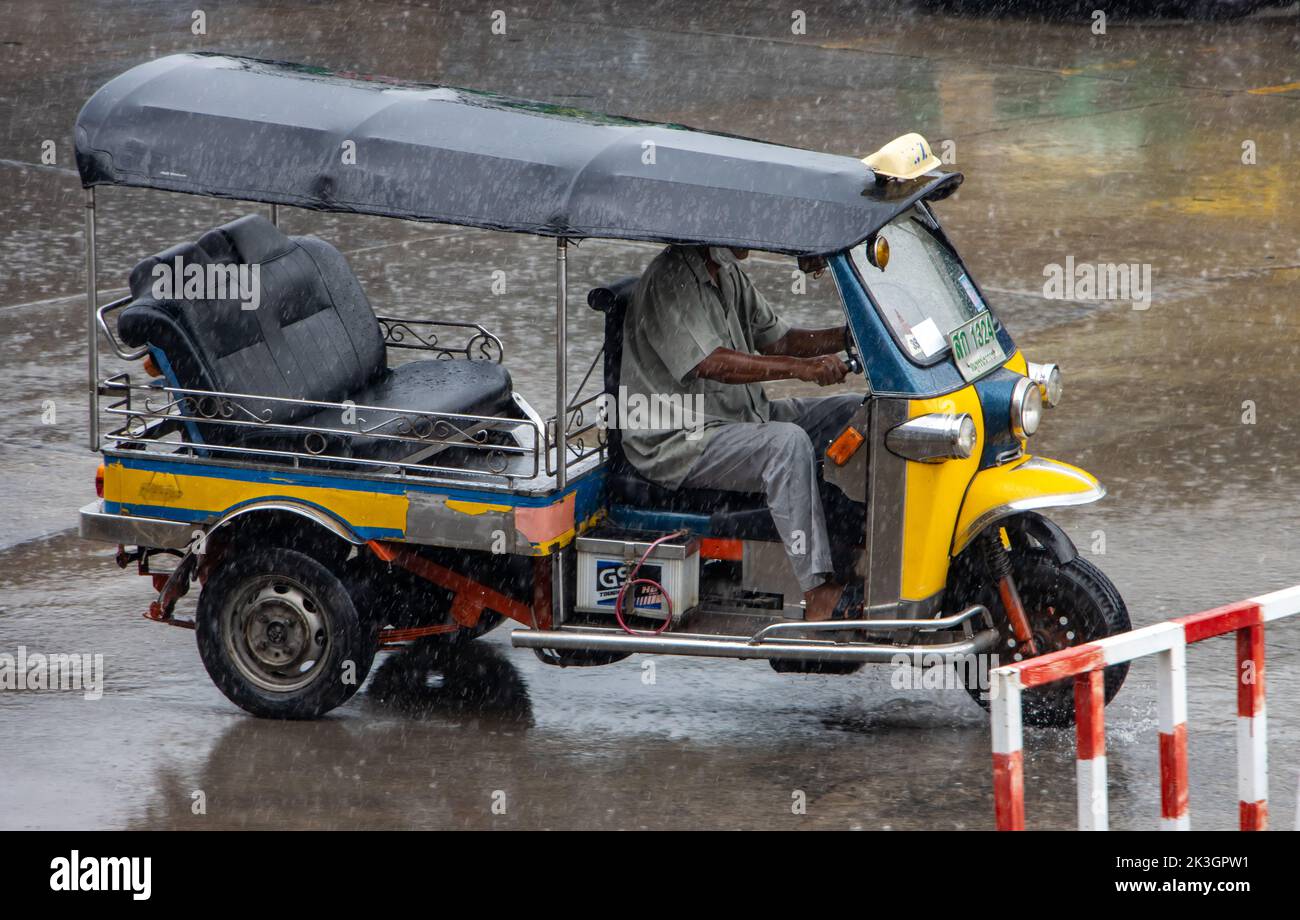 SAMUT PRAKAN, THAILAND, SEP 23 2022, An empty Tuk Tuk motor tricycle is driving a city street in the rain Stock Photo