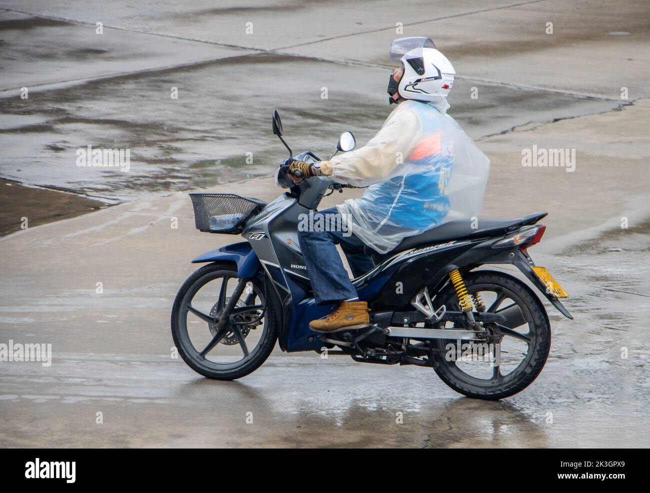 SAMUT PRAKAN, THAILAND, SEP 23 2022, A moto taxi driver in a raincoat is looking at the sky Stock Photo