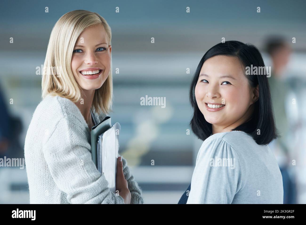 Heading to class. Two young students smiling while looking at the camera. Stock Photo