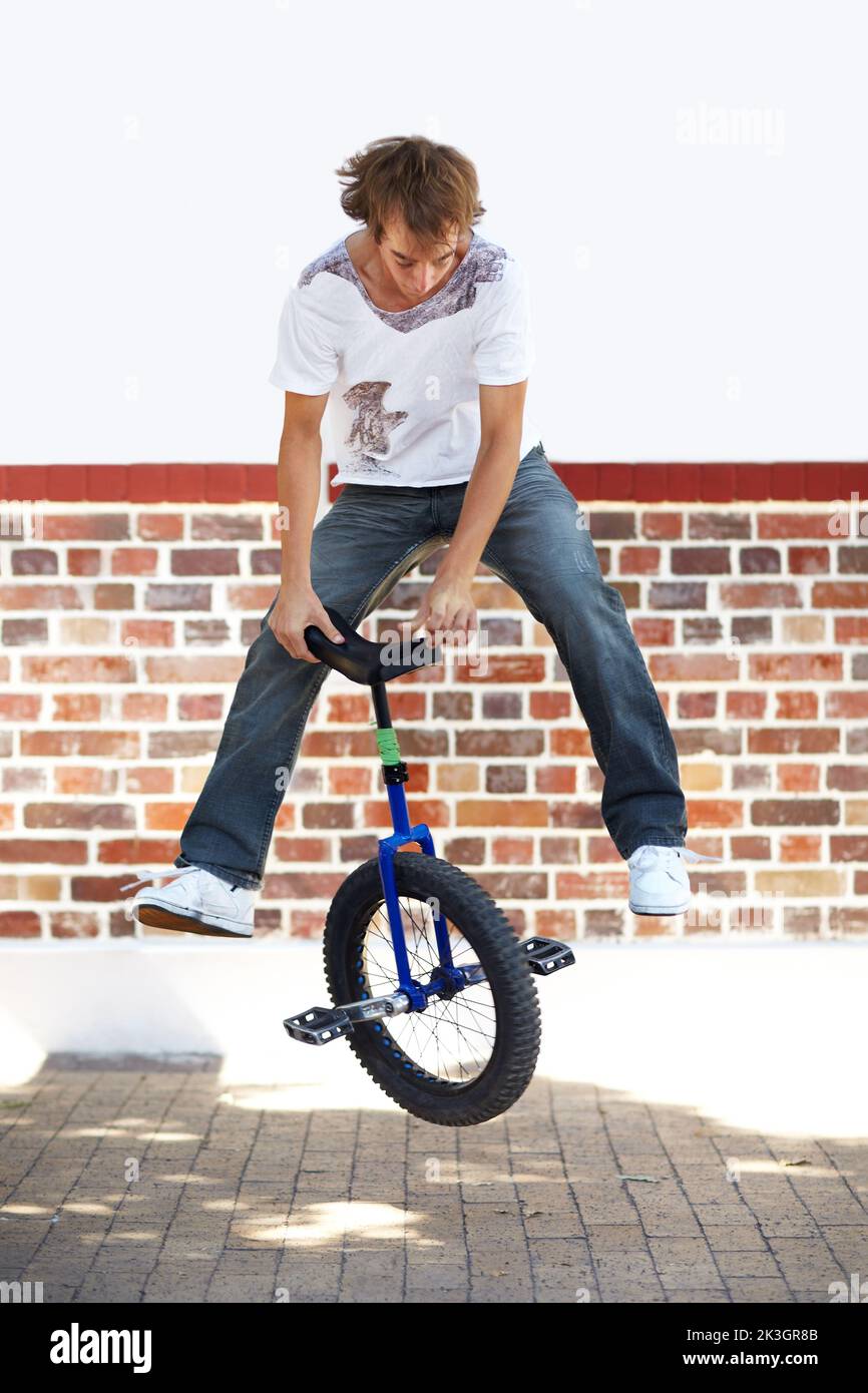 Turning seats. Full-length shot of a young man riding a unicycle. Stock Photo