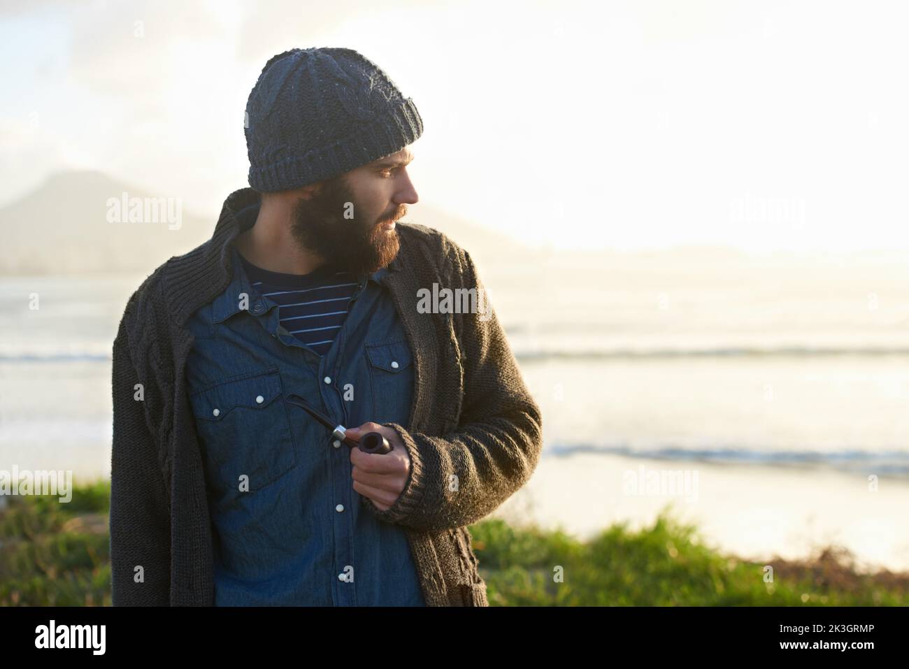 Smoking a pipe. a bearded man smoking a pipe outside. Stock Photo
