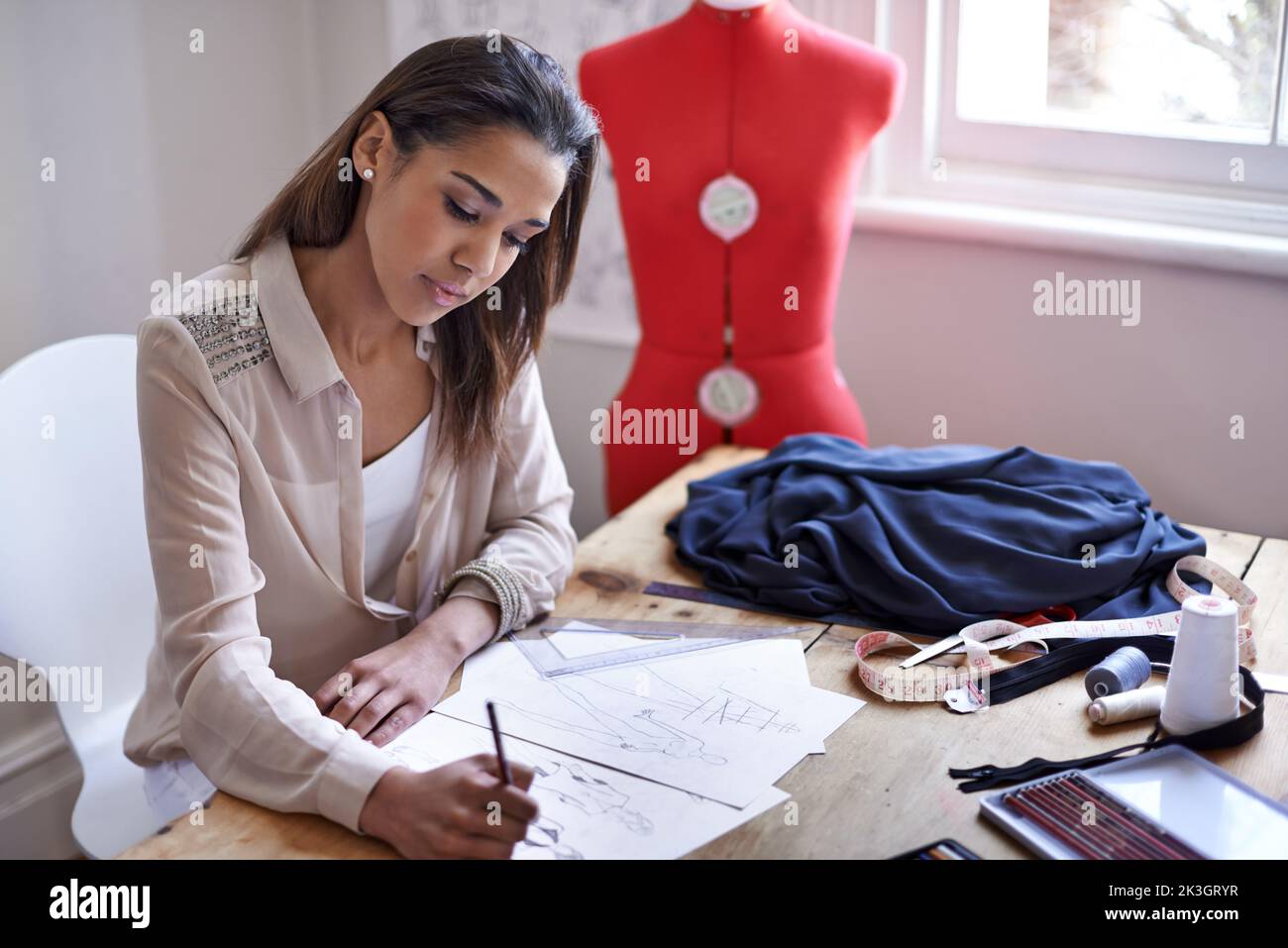 Coming up with new style trends. A fashion designer drawing sketches in ...