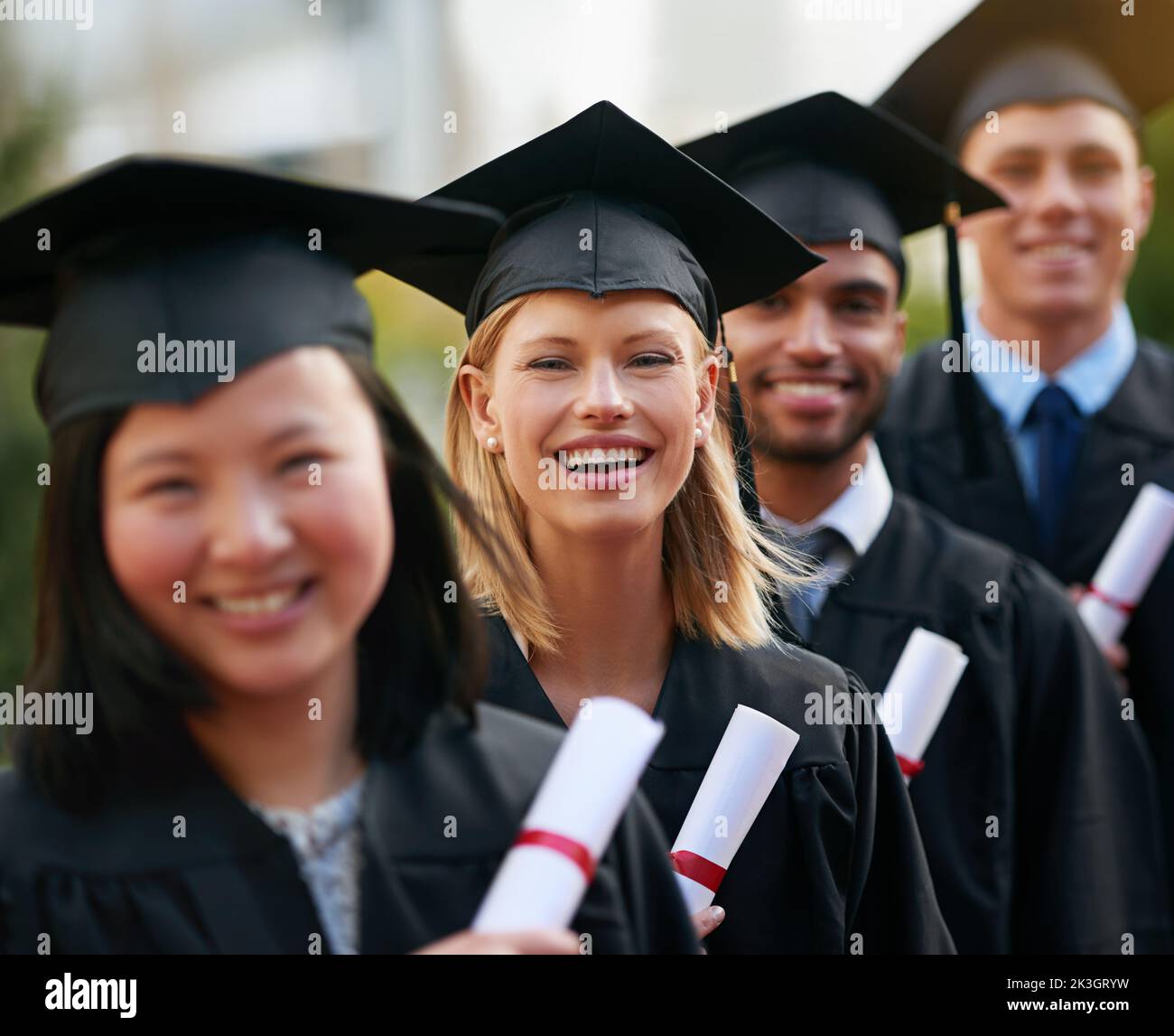 Let new adventures begin...A group of college graduates standing in cap and gown and holding their diplomas. Stock Photo