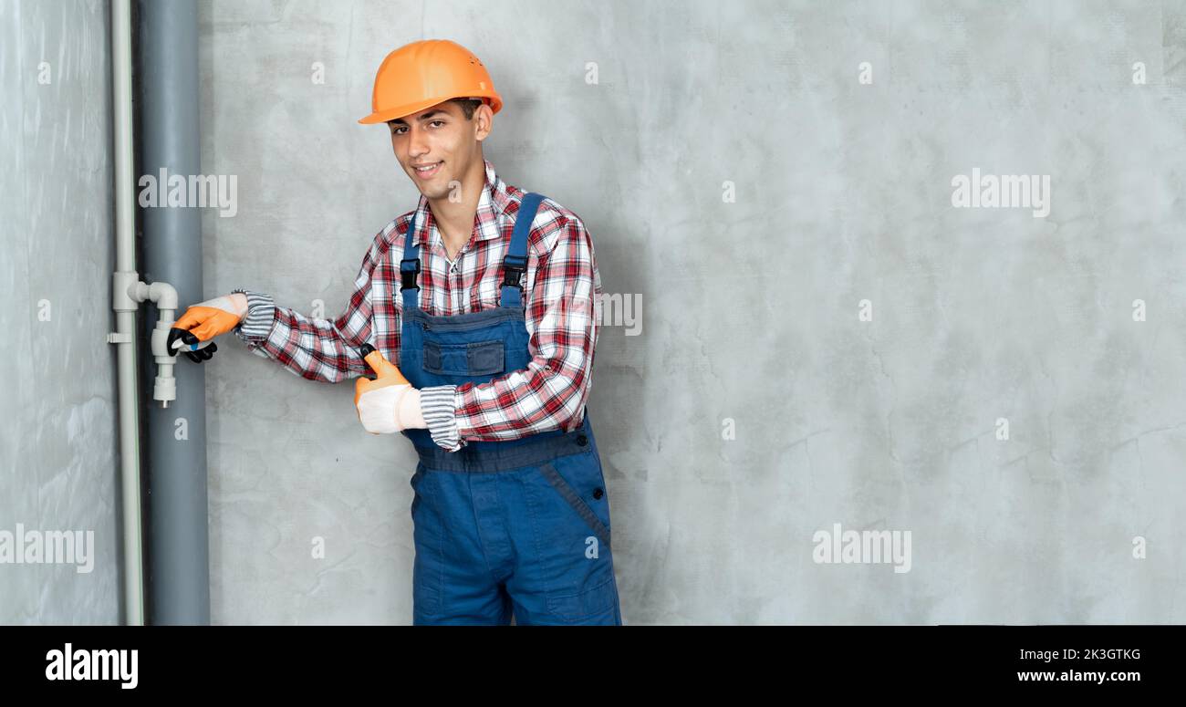 Arabic male plumber holding pipe crane on a construction site indoors, home renovation concept. Banner Stock Photo