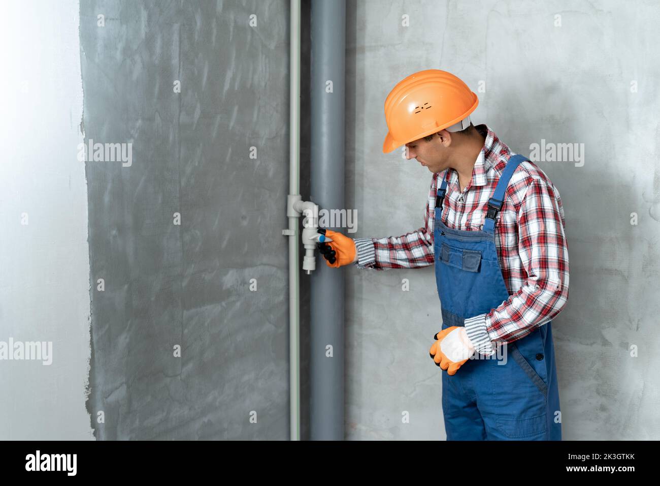 male plumber holding pipe on a construction site indoors, low angle view of technician, home renovation concept Stock Photo