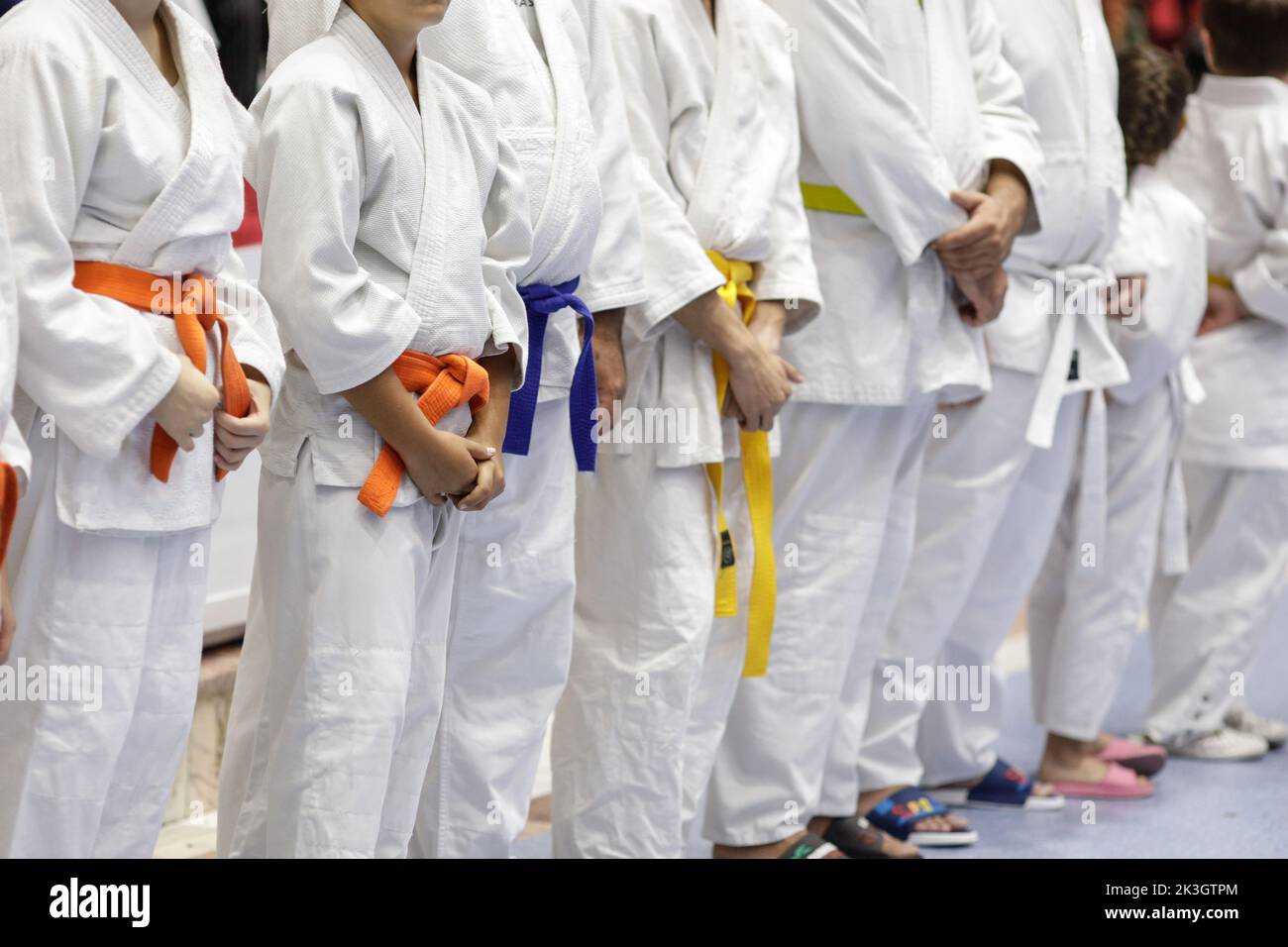 Shallow depth of field (selective focus) details with both children and adults martial arts students in their specific outfits (kimonos). Stock Photo