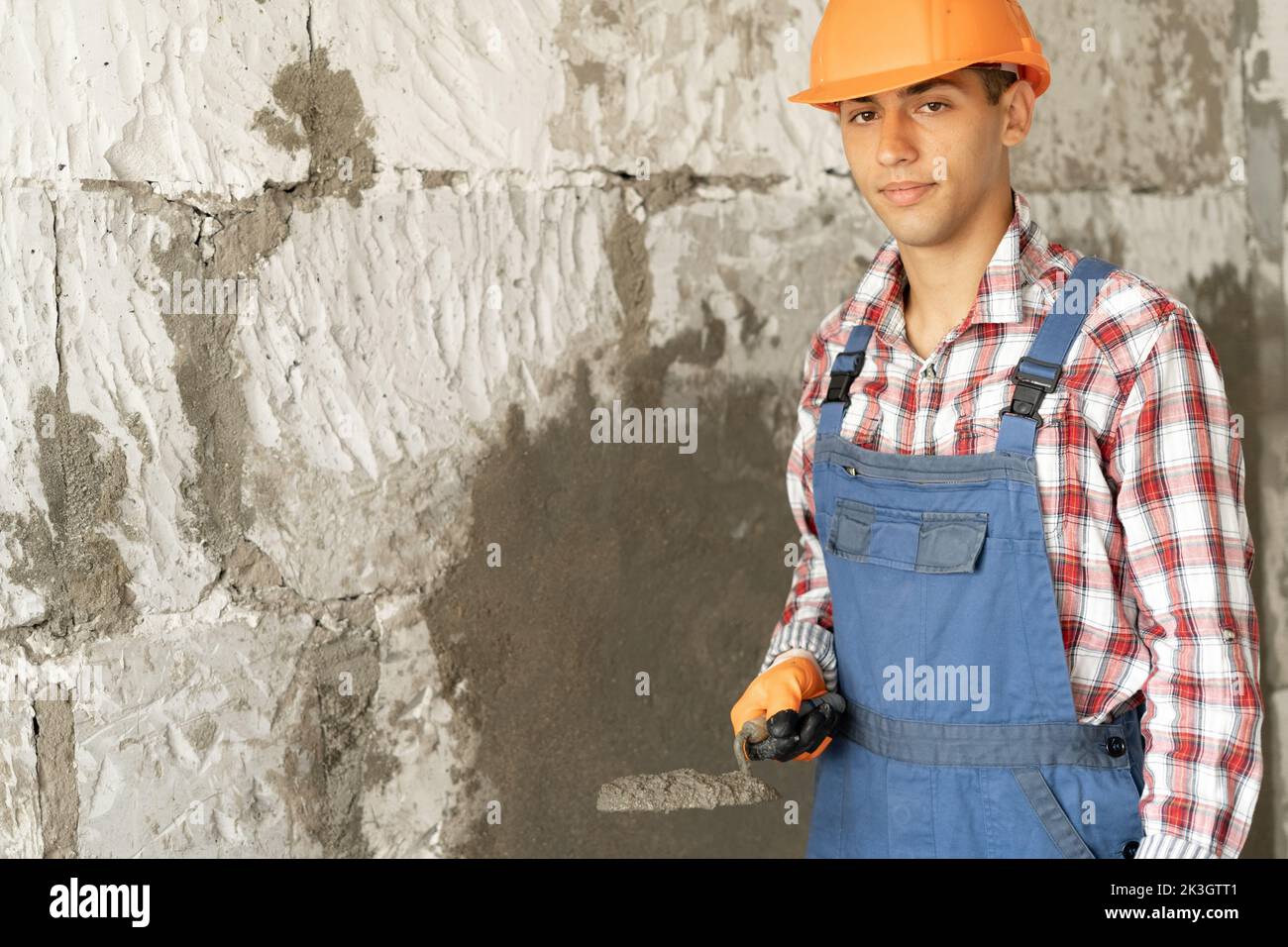 close up of builder worker plasterer holding trowel to plastering cement wall in construction site. building construction work and industry concept Stock Photo