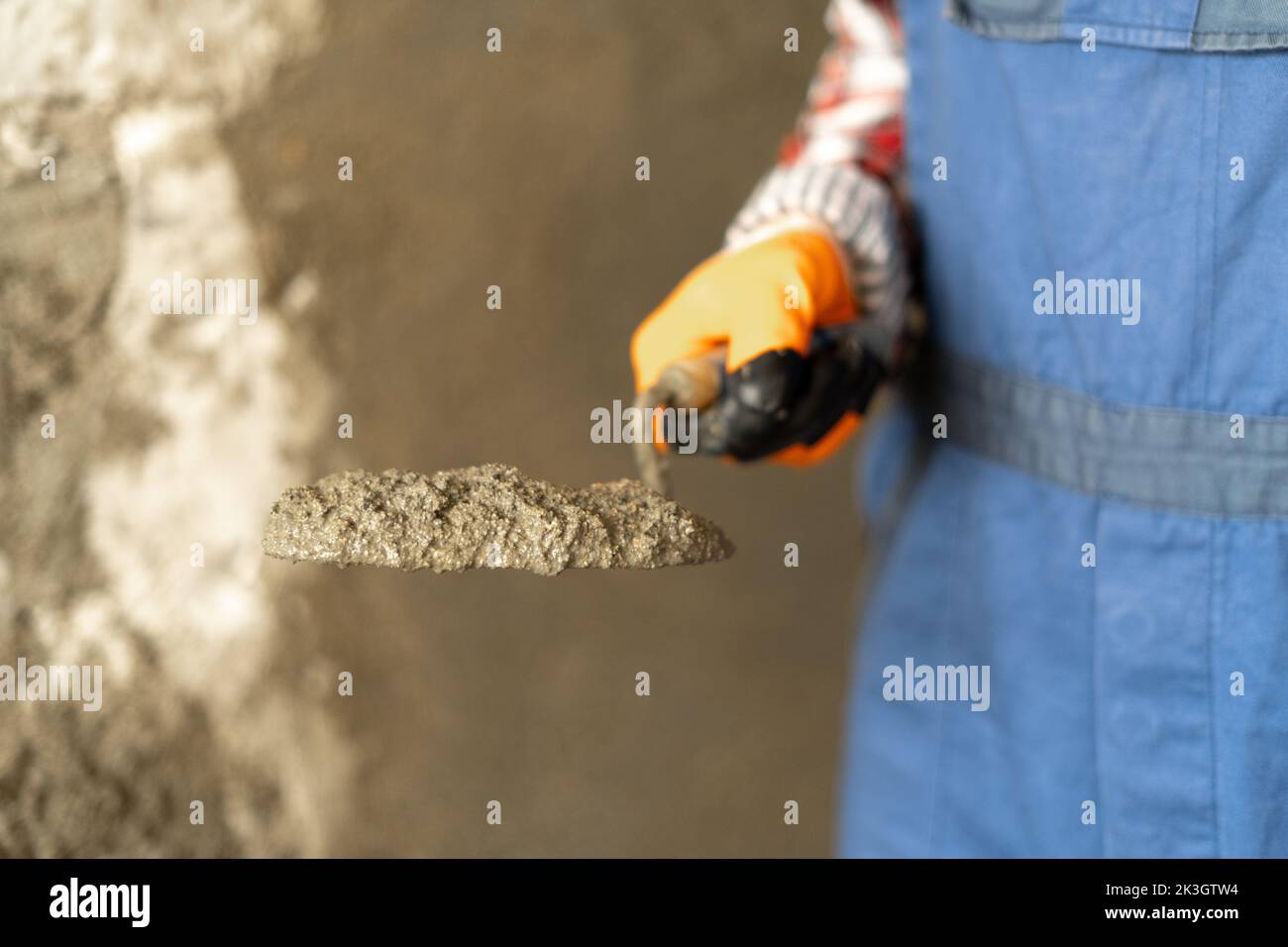 Hands man plasterer construction worker at work with trowel, plastering a wall cement mortar, closeup Stock Photo