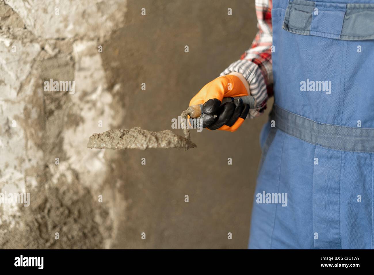Hands man plasterer construction worker at work with trowel, plastering a wall cement mortar, close up Stock Photo