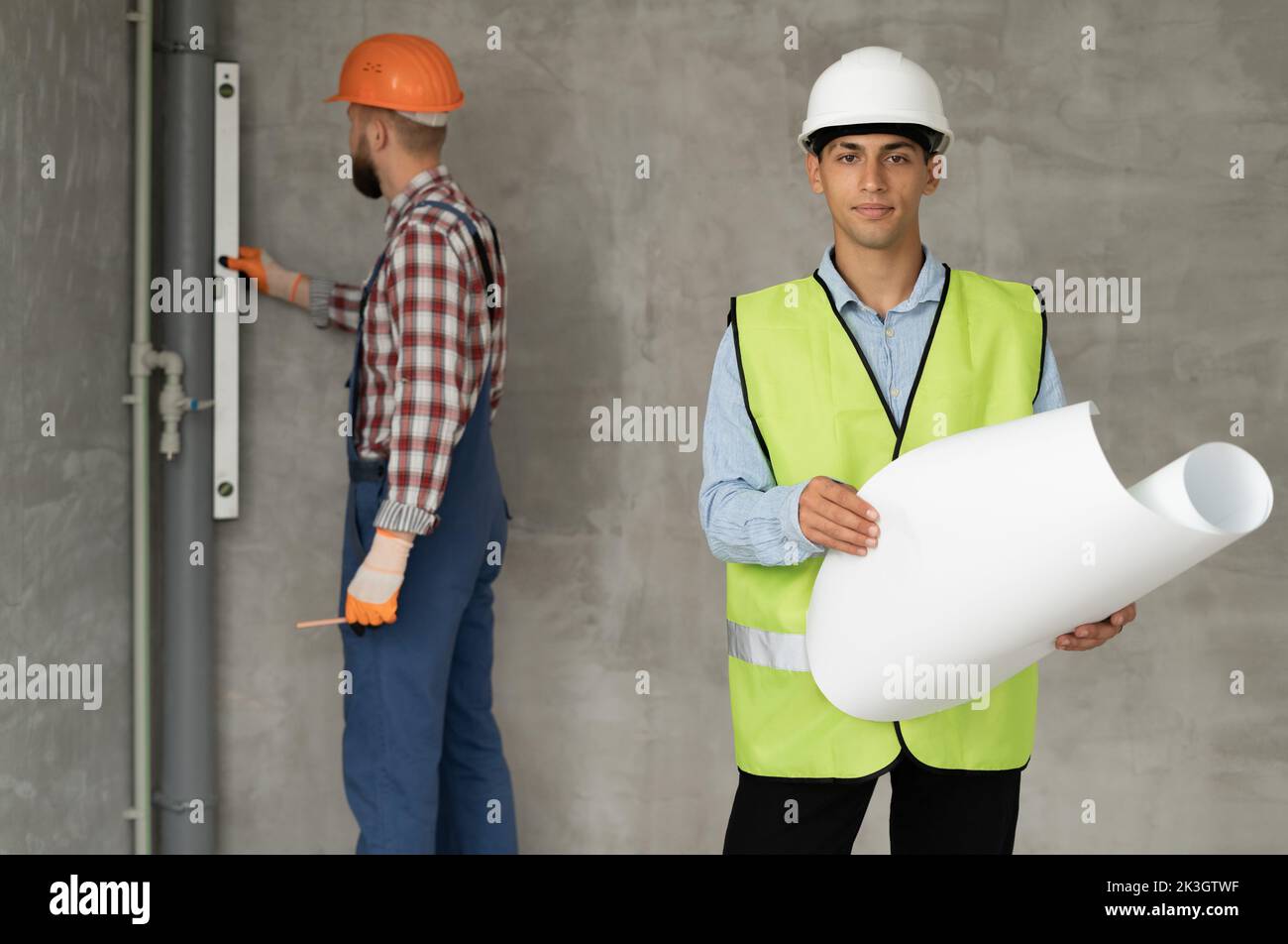 construction site engineer or architect with blueprints and builder with level in hands. Construction, repair and remodeling concept Stock Photo