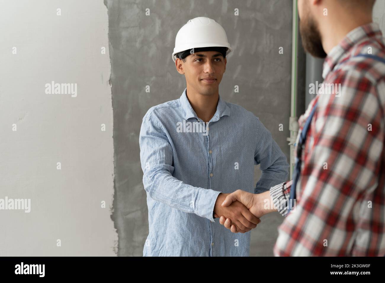Contractor and client shaking hands with team builder in renovation site. Partnership, contractor concept Stock Photo