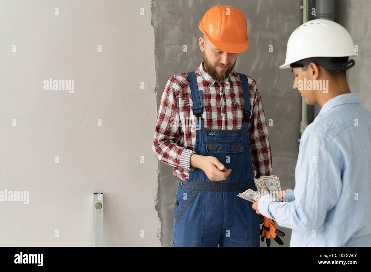 Payday. Illegal Construction Worker Receiving Customer's Money, civil engineer giving money to a worker at a construction site. Paying House Repair De Stock Photo
