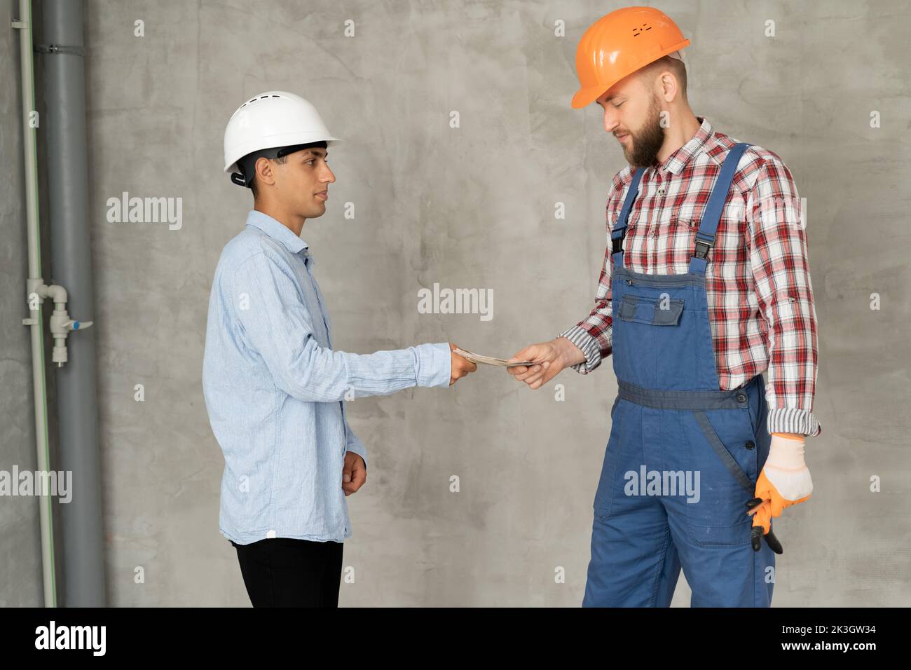 Man manager pays for the work of foreman builder repairman with dollar money. construction site concept. Focus on hands with money. business man maste Stock Photo