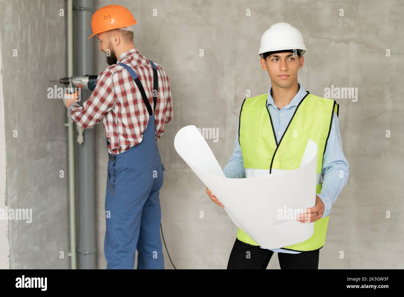 home repairs. Two young man architect with blueprint and builder with level near wall on a building construction site. Teamwork repaur house. Repair, Stock Photo