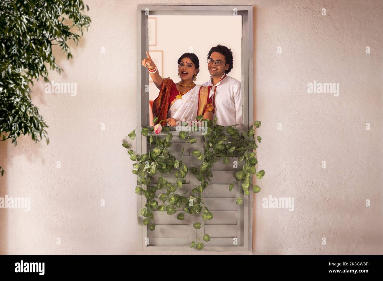 Bengali couple looking and pointing outside while standing by window