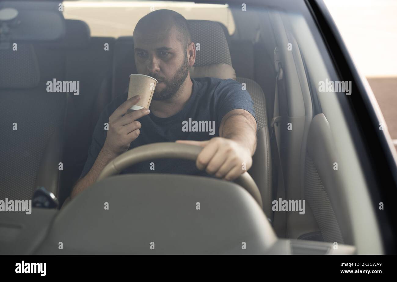 Millennial man or driver with takeaway coffee cup driving car. transport, vehicle and people concept. don't sleep and drive Stock Photo