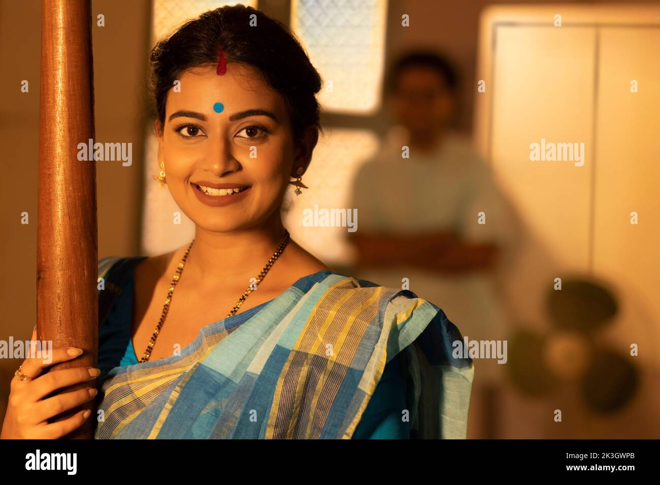 Portrait of Bengali woman at home and husband standing away Stock Photo