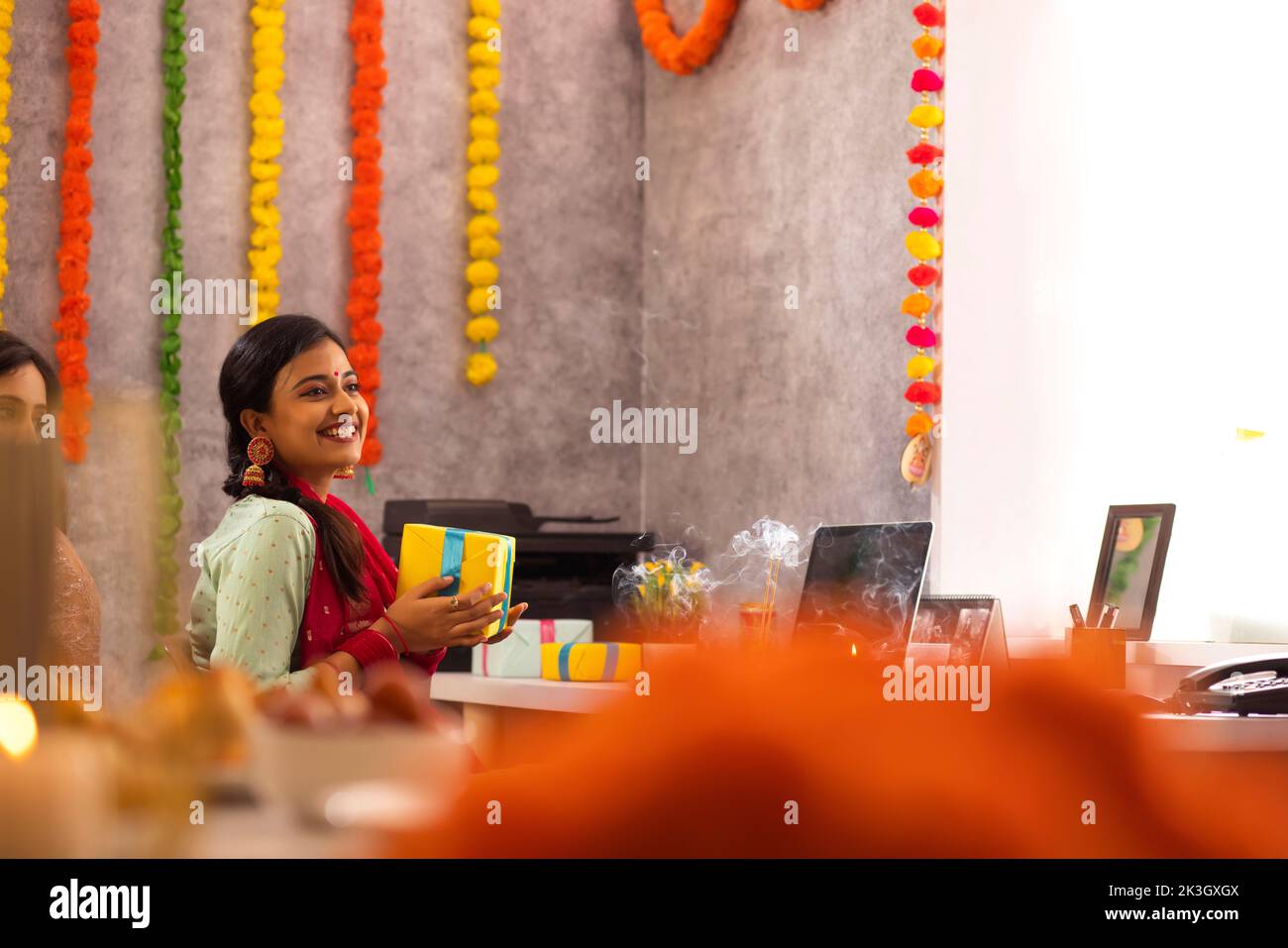 Female employees holding gifts in office during Diwali celebration Stock Photo