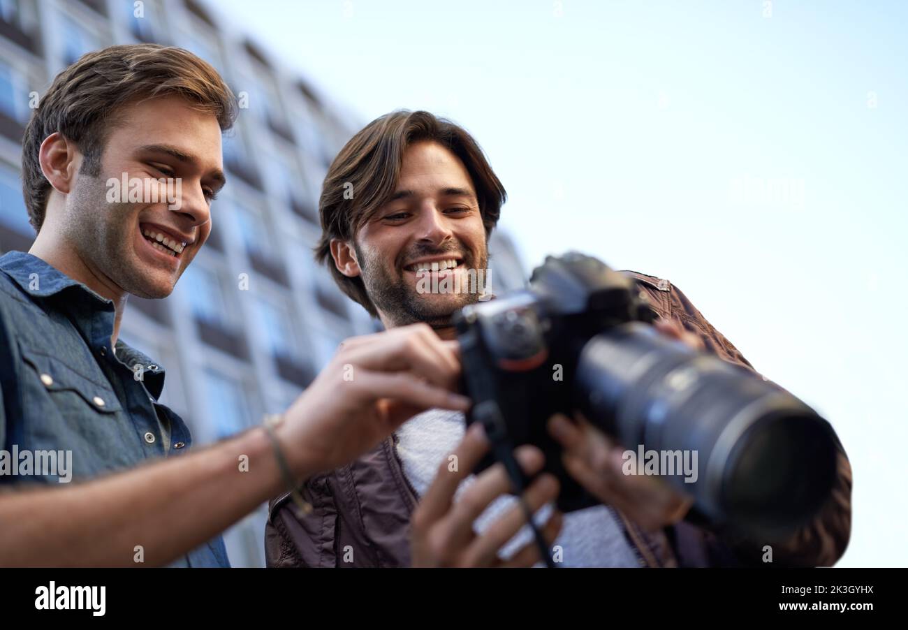 Hes proud of his photographs. Low angle shot of two men looking at the lcd screen on a digital camera. Stock Photo