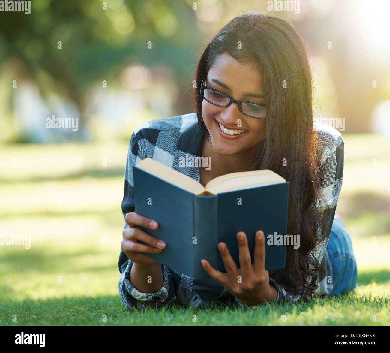 Woman lying down with hardcover book reading Stock Photo - Alamy