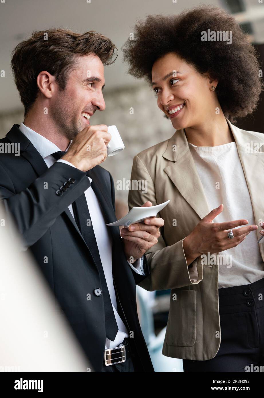 Portrait of businessman drinking coffee, talking to woman colleague Stock Photo