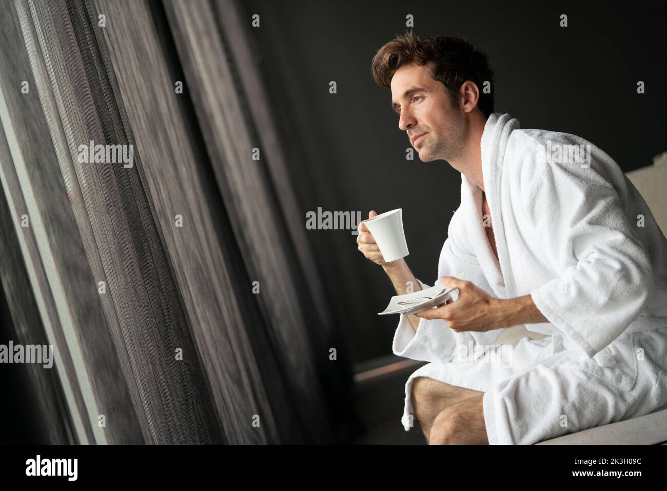 Young man in bathrobe drinking coffee at home Stock Photo