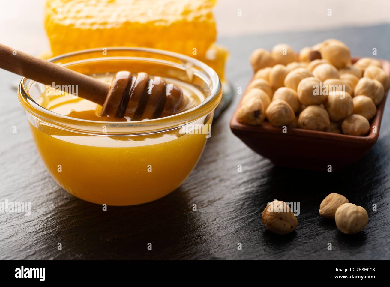 Slate tray with honey hazelnuts and honeycomb on kitchen table Stock Photo