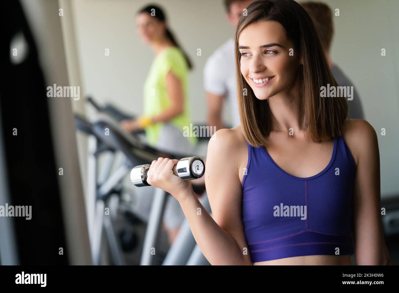 Attractive young woman working out with dumbbells at a gym. Stock Photo