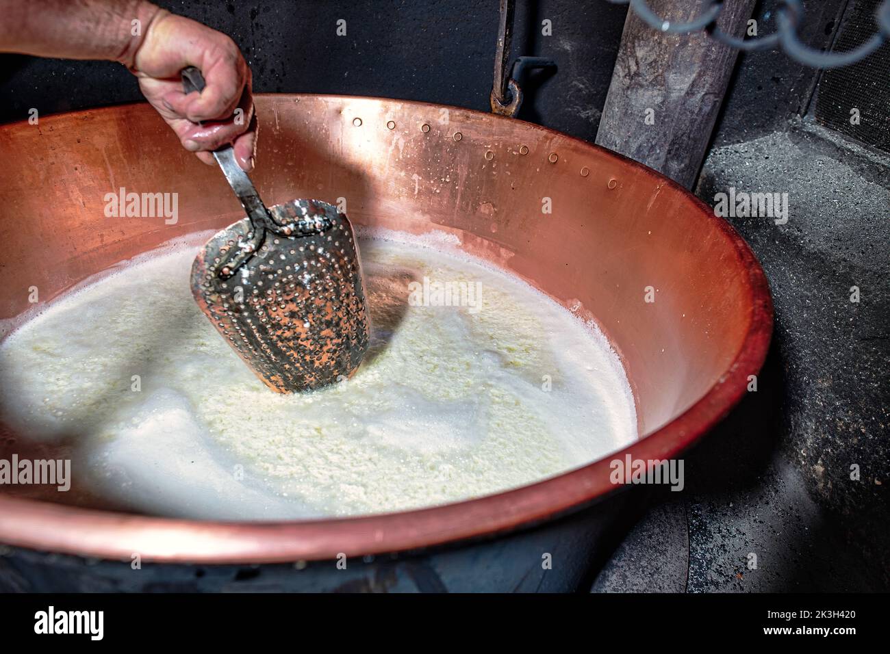 Perforated copper plucker mixes genuine mountain pasture ricotta from northern Italy Stock Photo