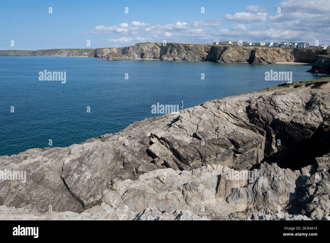 A lone fisherman on the rugged rocks of the cliffs at Porth, north Cornwall, England with the ocean beyond. Stock Photo