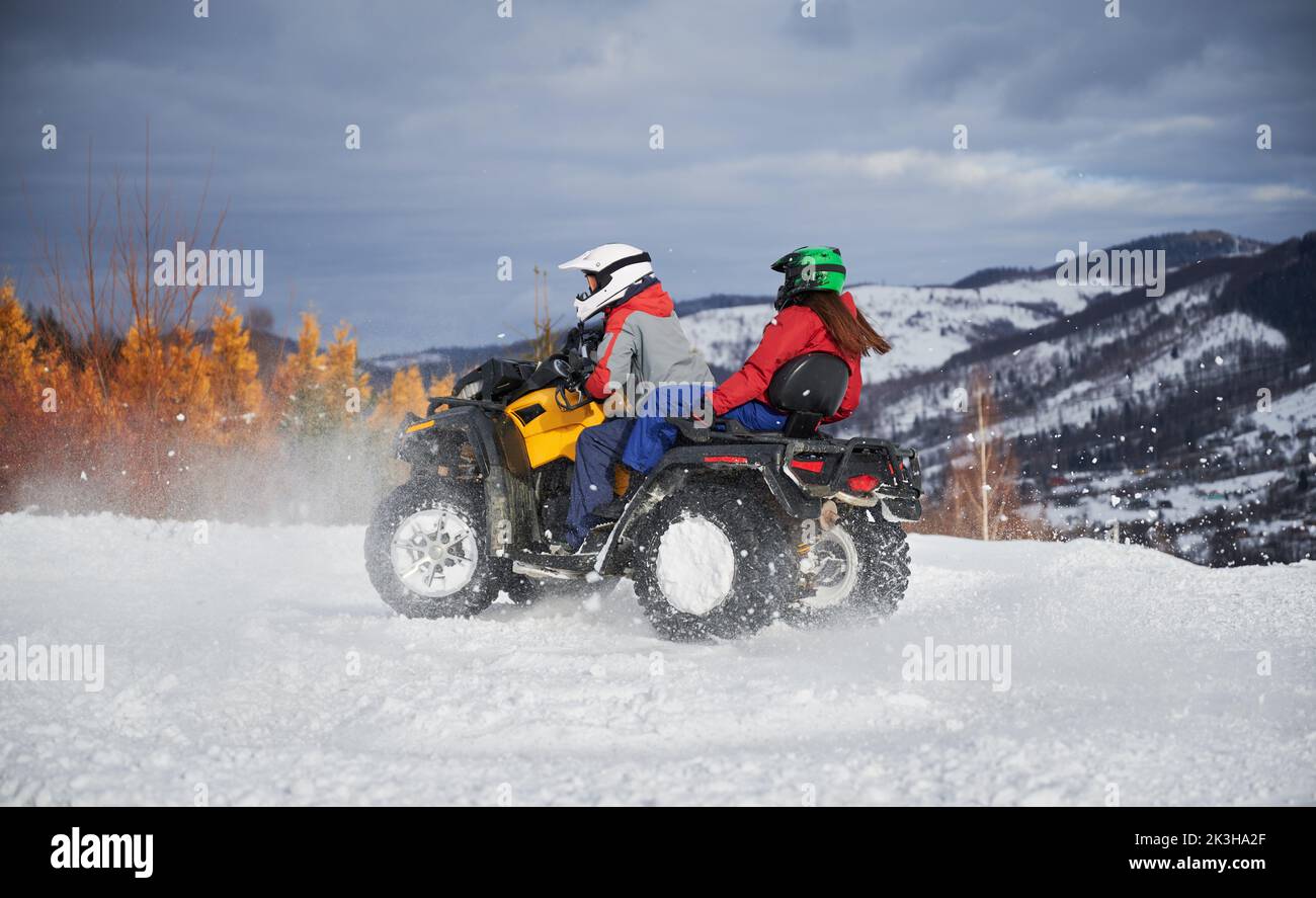 Portrait of man and woman riding on offroad four-wheeler ATV. Concept of active leisure and winter activities. Stock Photo