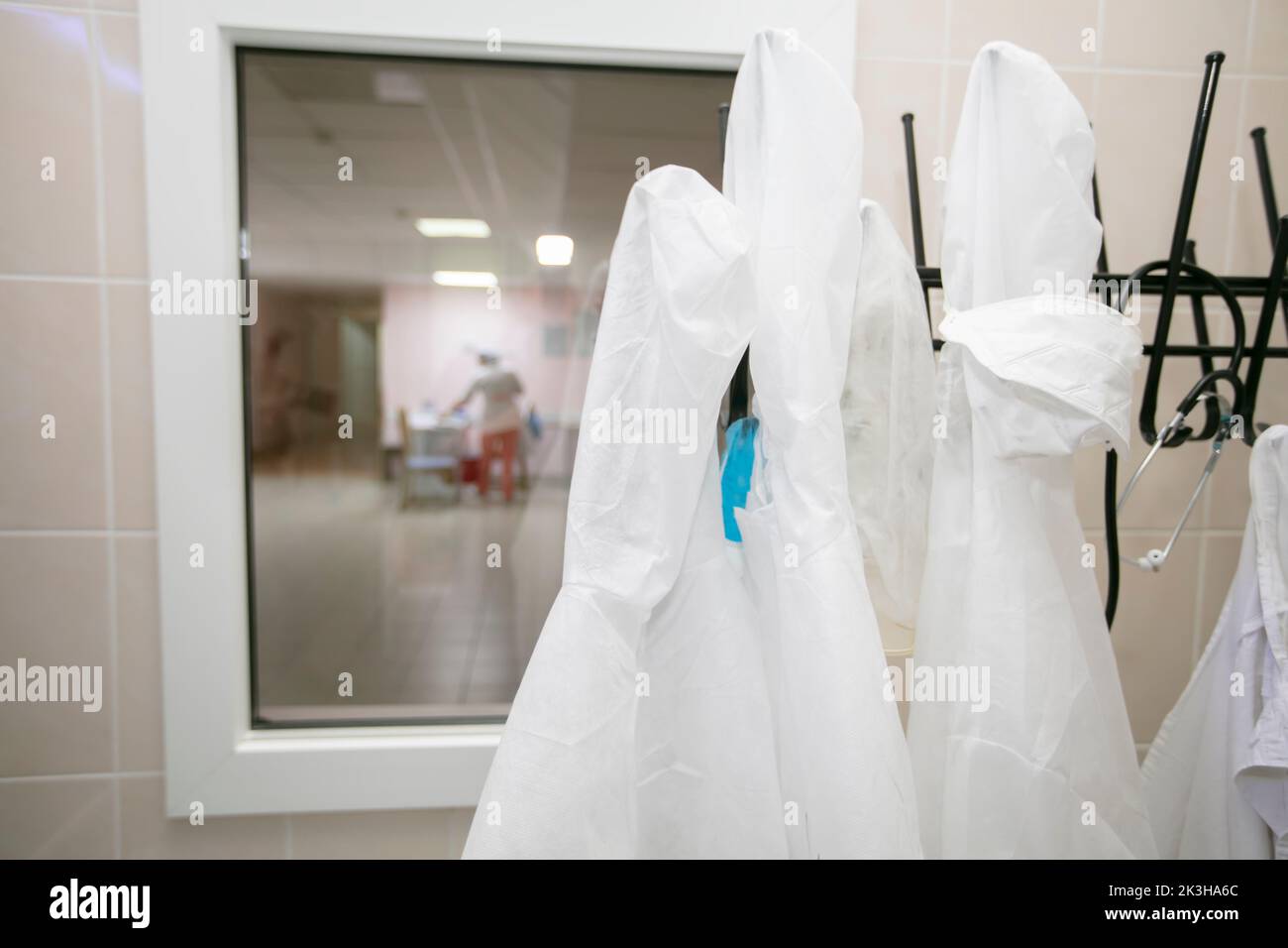 White medical gowns hang on hangers in the hospital Stock Photo - Alamy