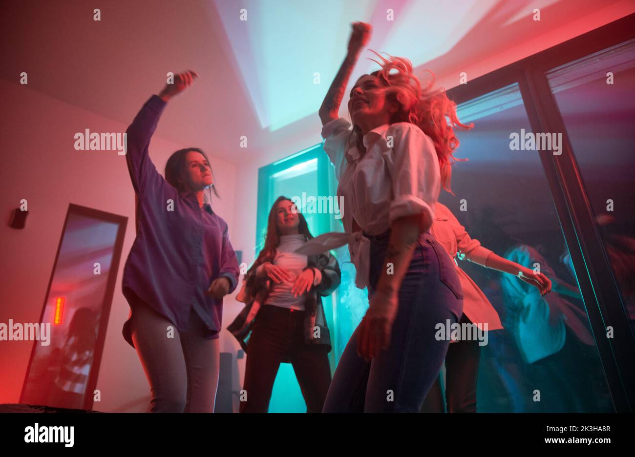 Young women having party inside contemporary barn house at night. Stock Photo