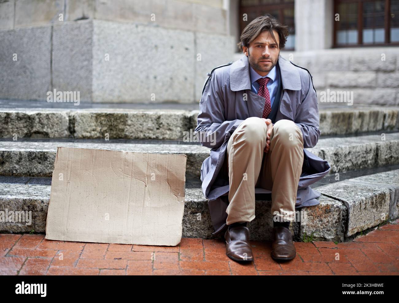 Will model for food. View of an unemployed businessman sitting on the steps begging for work. Stock Photo