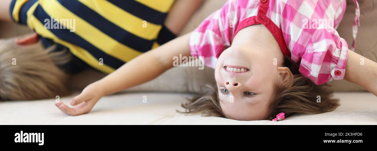 Children have fun at home, kids upside down on sofa, holiday at school Stock Photo