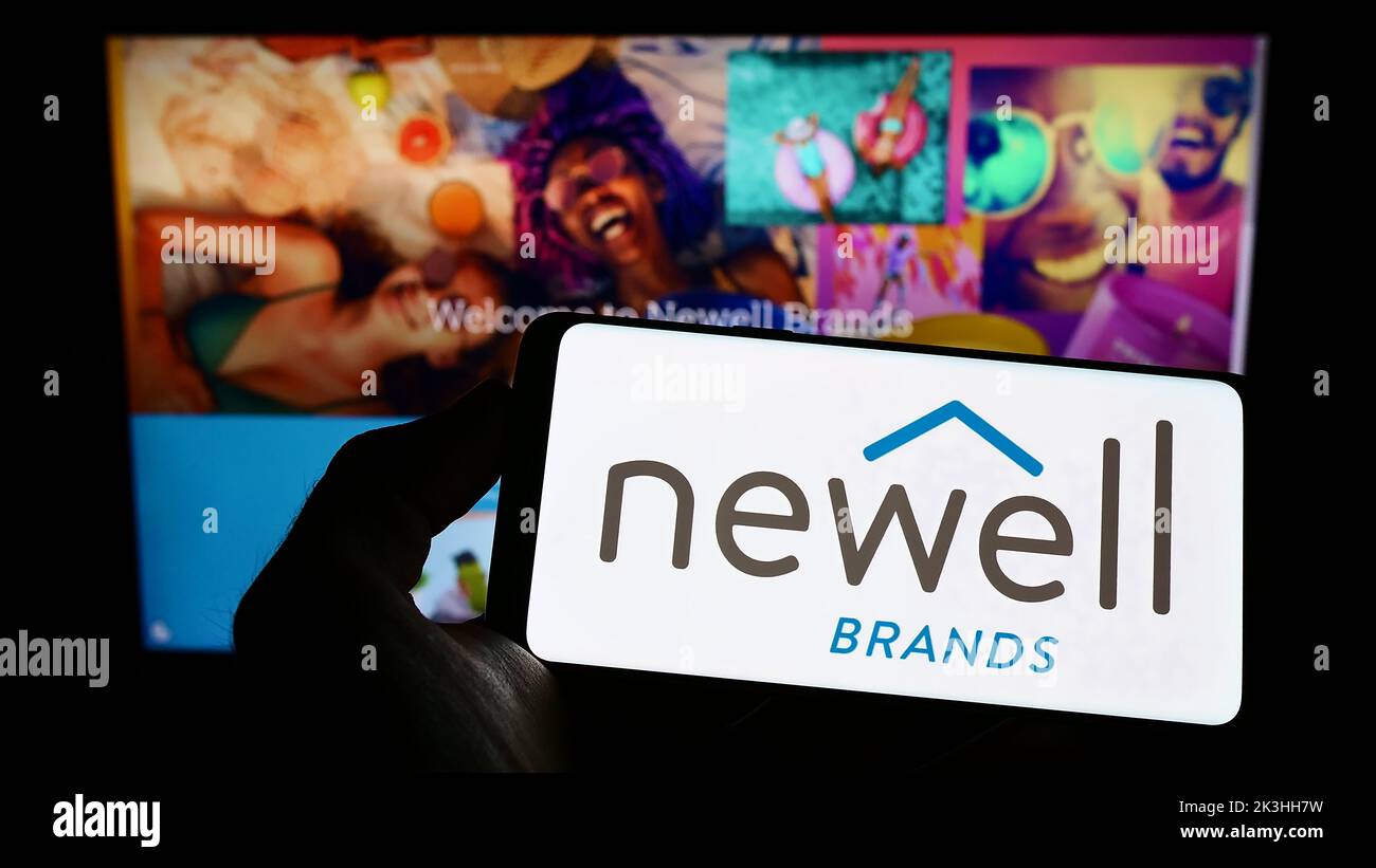 Person holding cellphone with logo of American consumer goods company Newell Brands Inc. on screen in front of webpage. Focus on phone display. Stock Photo