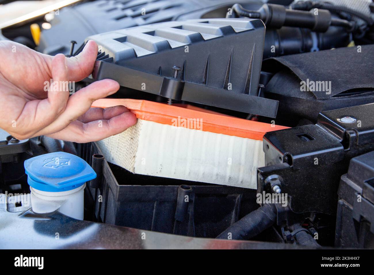 Replacing an old dirty air filter in the engine compartment of a car
