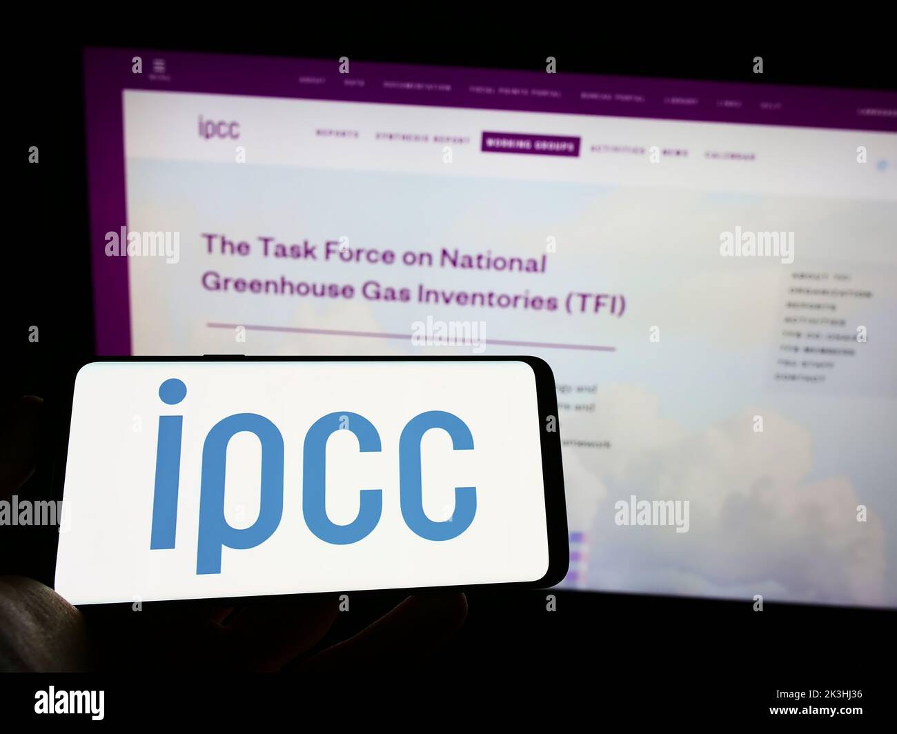 Person holding cellphone with logo of Intergovernmental Panel on Climate Change (IPCC) on screen in front of webpage. Focus on phone display. Stock Photo