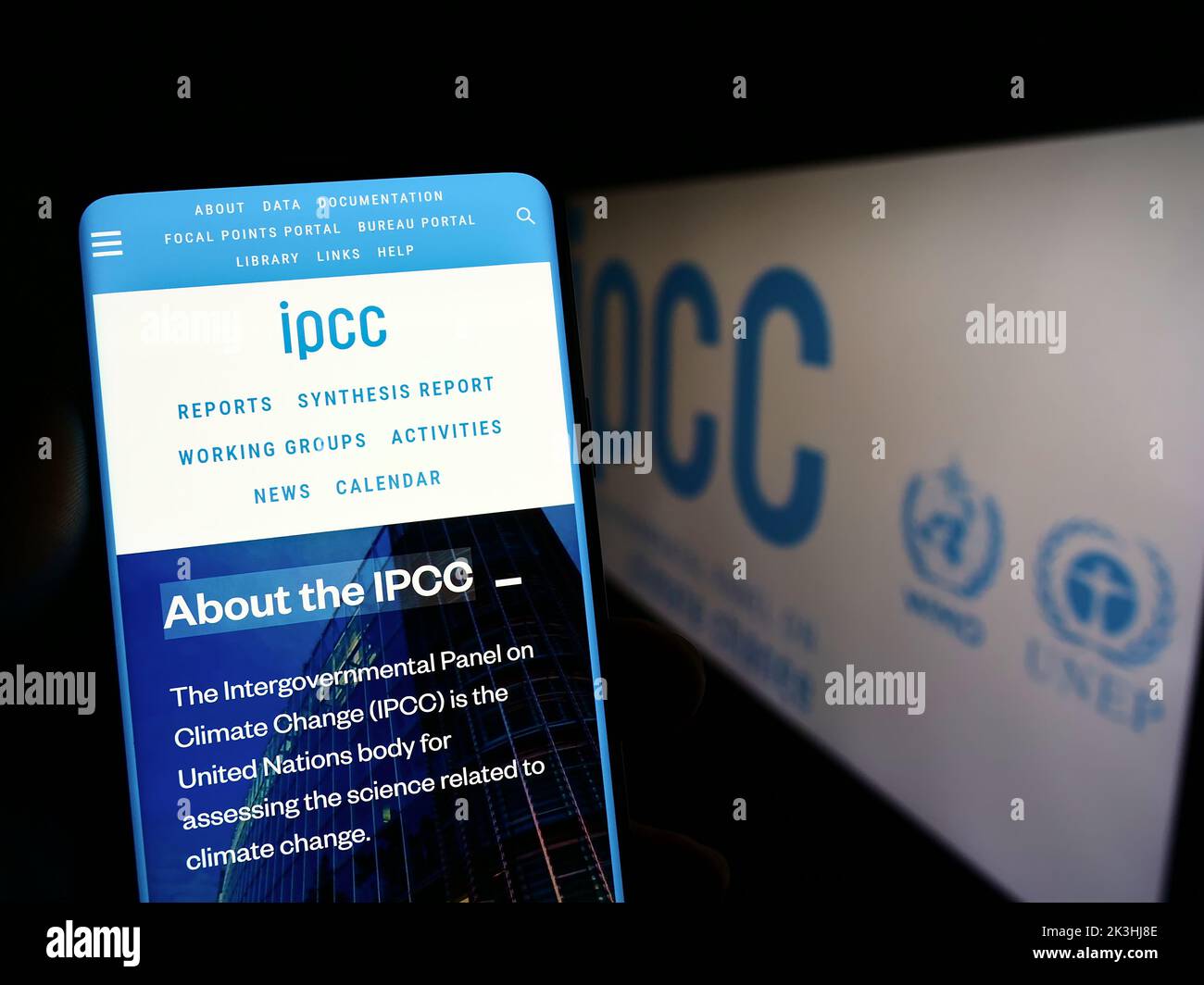Person holding mobile phone with webpage of Intergovernmental Panel on Climate Change (IPCC) on screen with logo. Focus on center of phone display. Stock Photo
