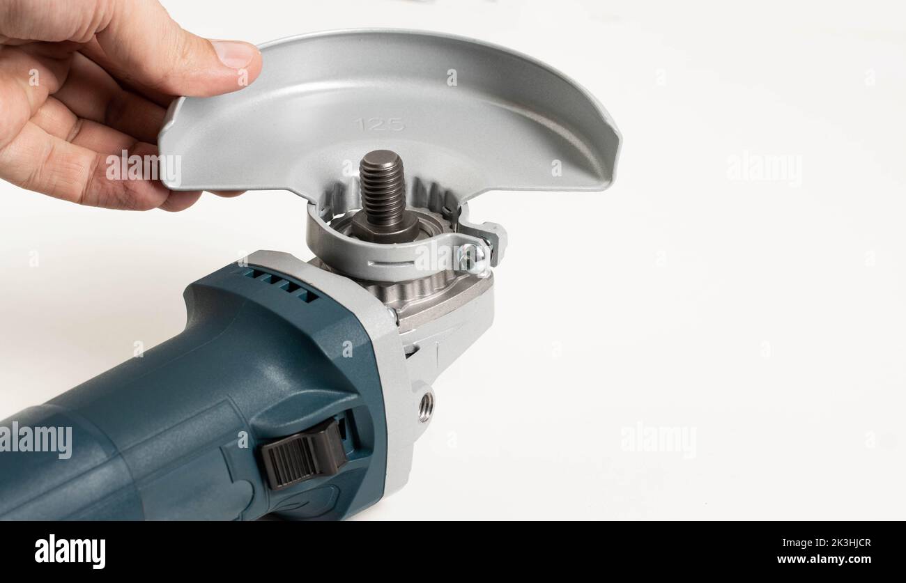 Installing the safety cover on an angle grinder, close-up. Safety precautions when working with construction power tools. Industry Stock Photo