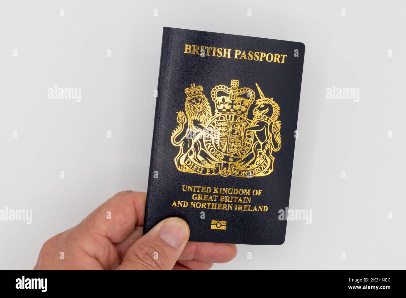 New blue British passport isolated on white background, held by a white male hand, uk Stock Photo
