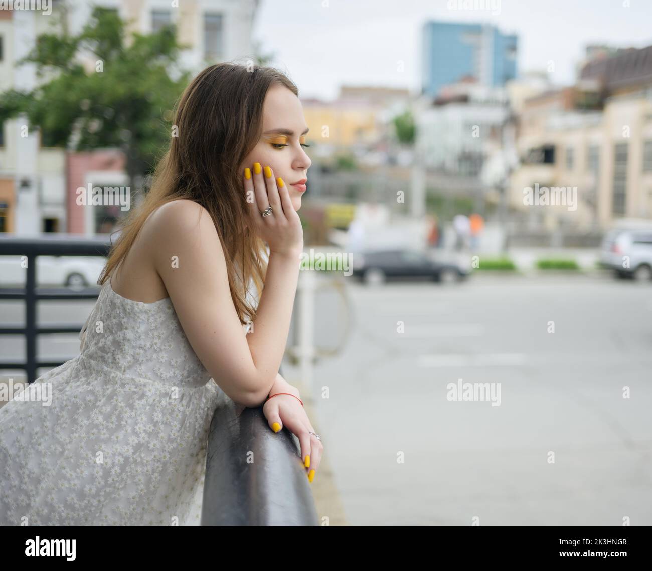 City portrait of beautiful young woman in white dress. Stock Photo